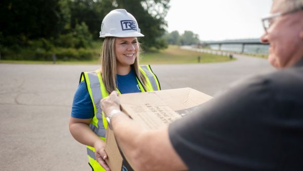 woman in work vest helping someone with carrying a package